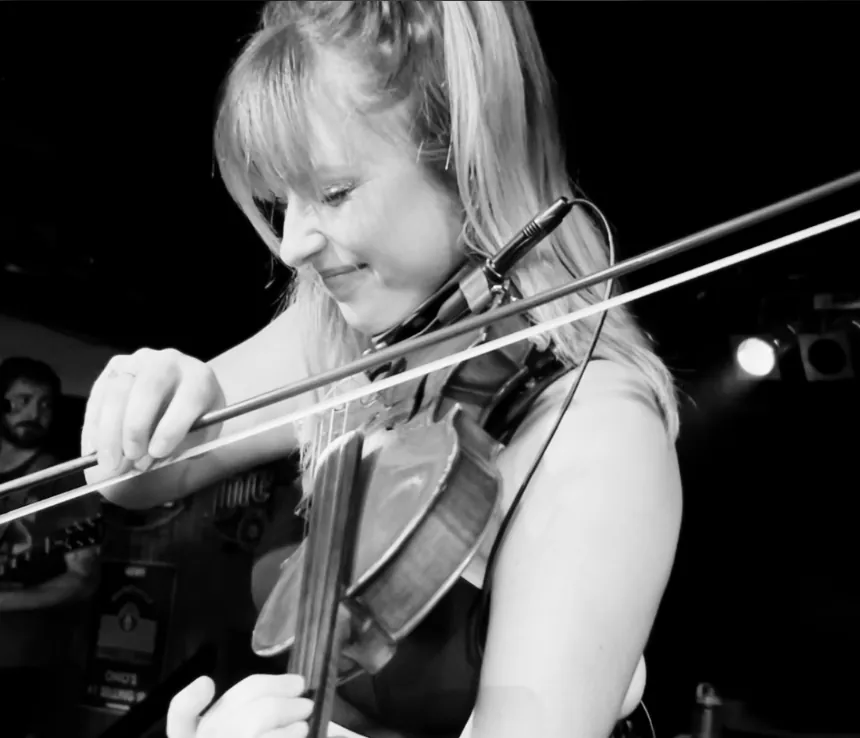 Becca playing violin on stage, in black and white
