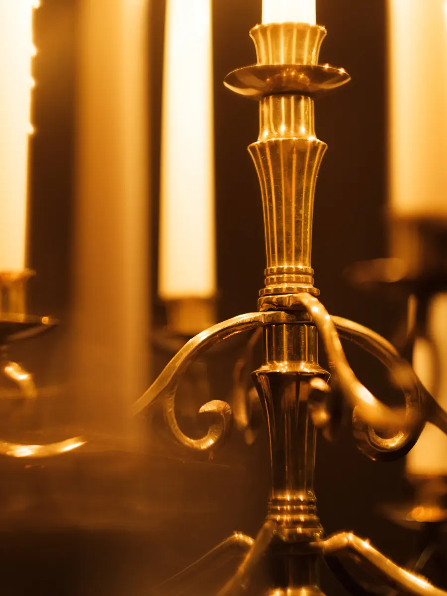 A close view of a brass candelabra glowing in candlelight