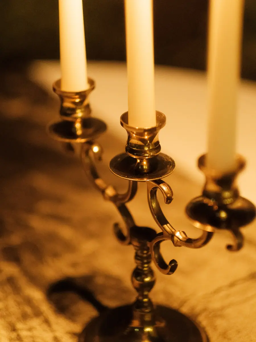 A three arm brass candelabra seen from a low angle on a white linen table