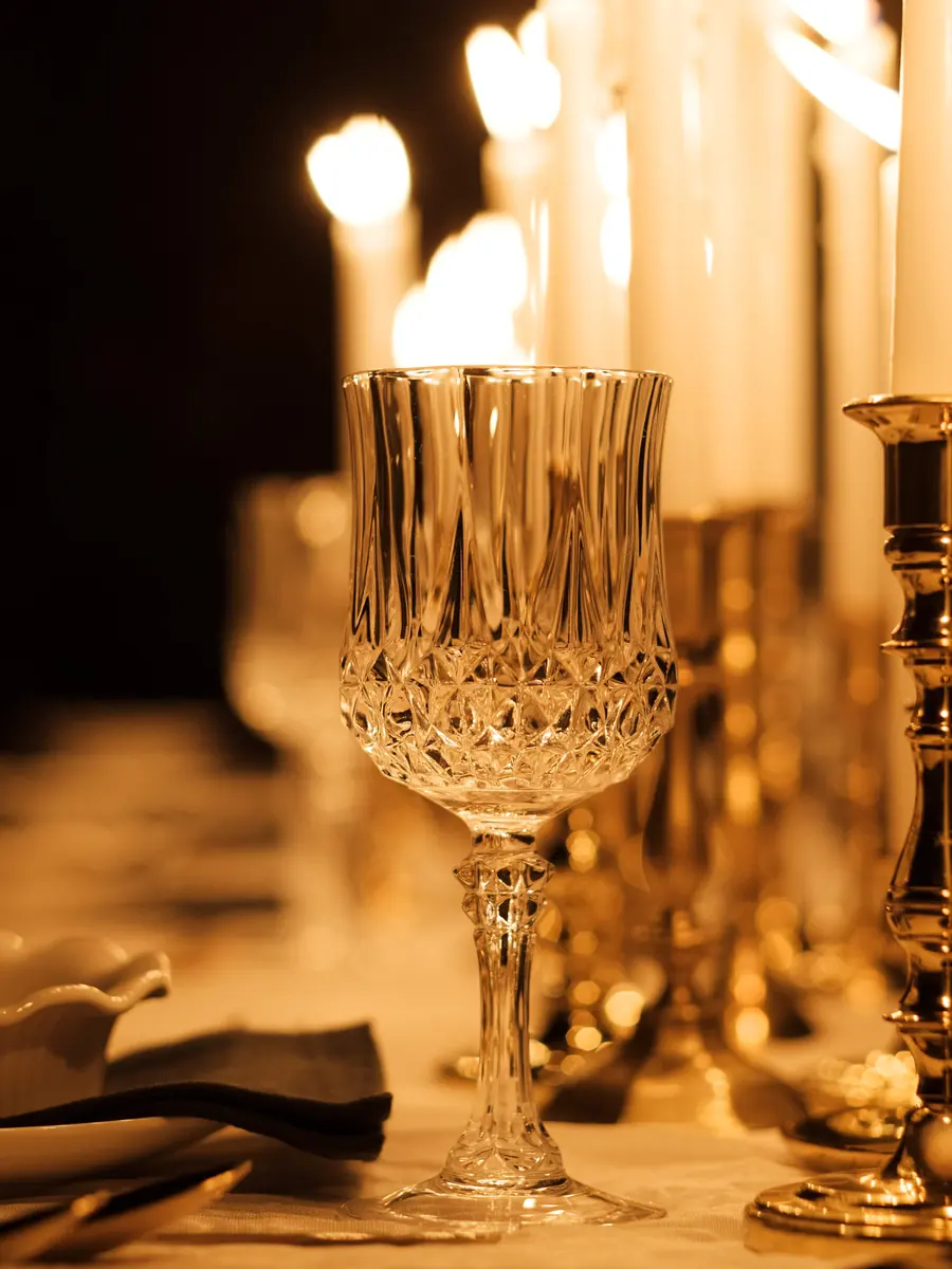 A crystal goblet in front of a cluster of lit tapers