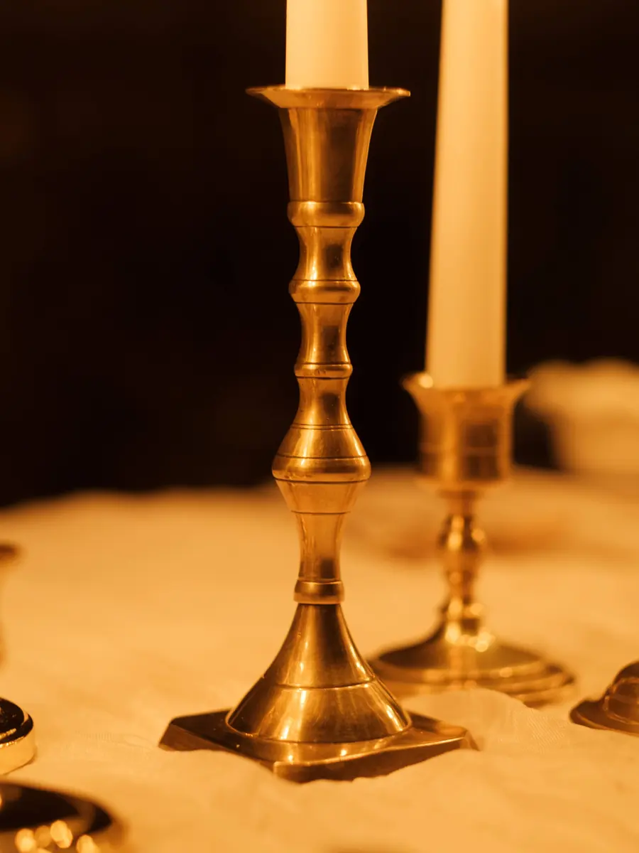 Brass candlesticks of different heights holding cream tapers
